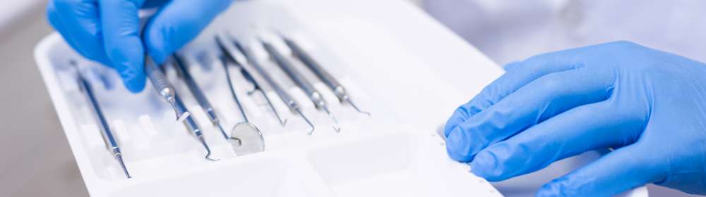 Dentist picking up dental tool at dental clinic